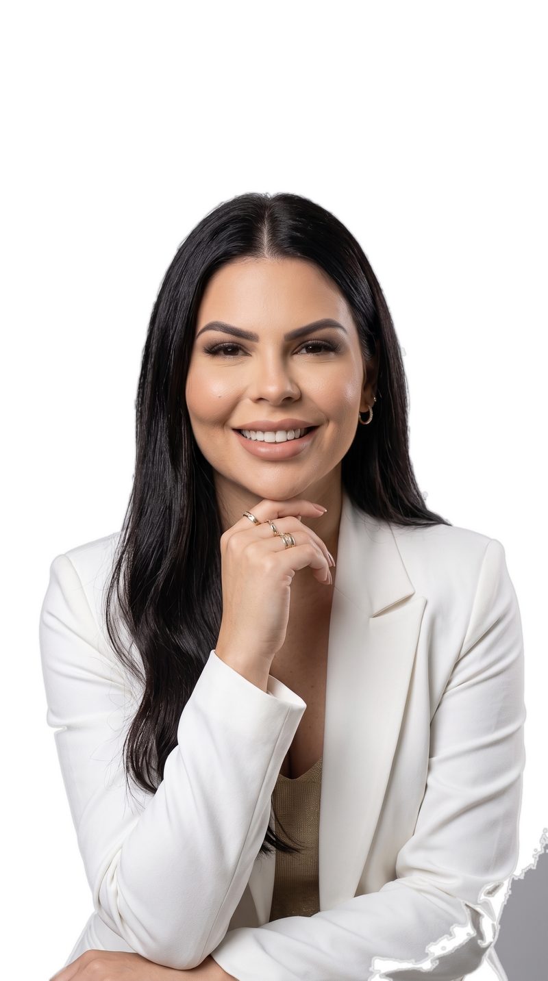 Dra. Carolina Vasconcelos sorrindo, de blazer branco, com a mão apoiada no queixo